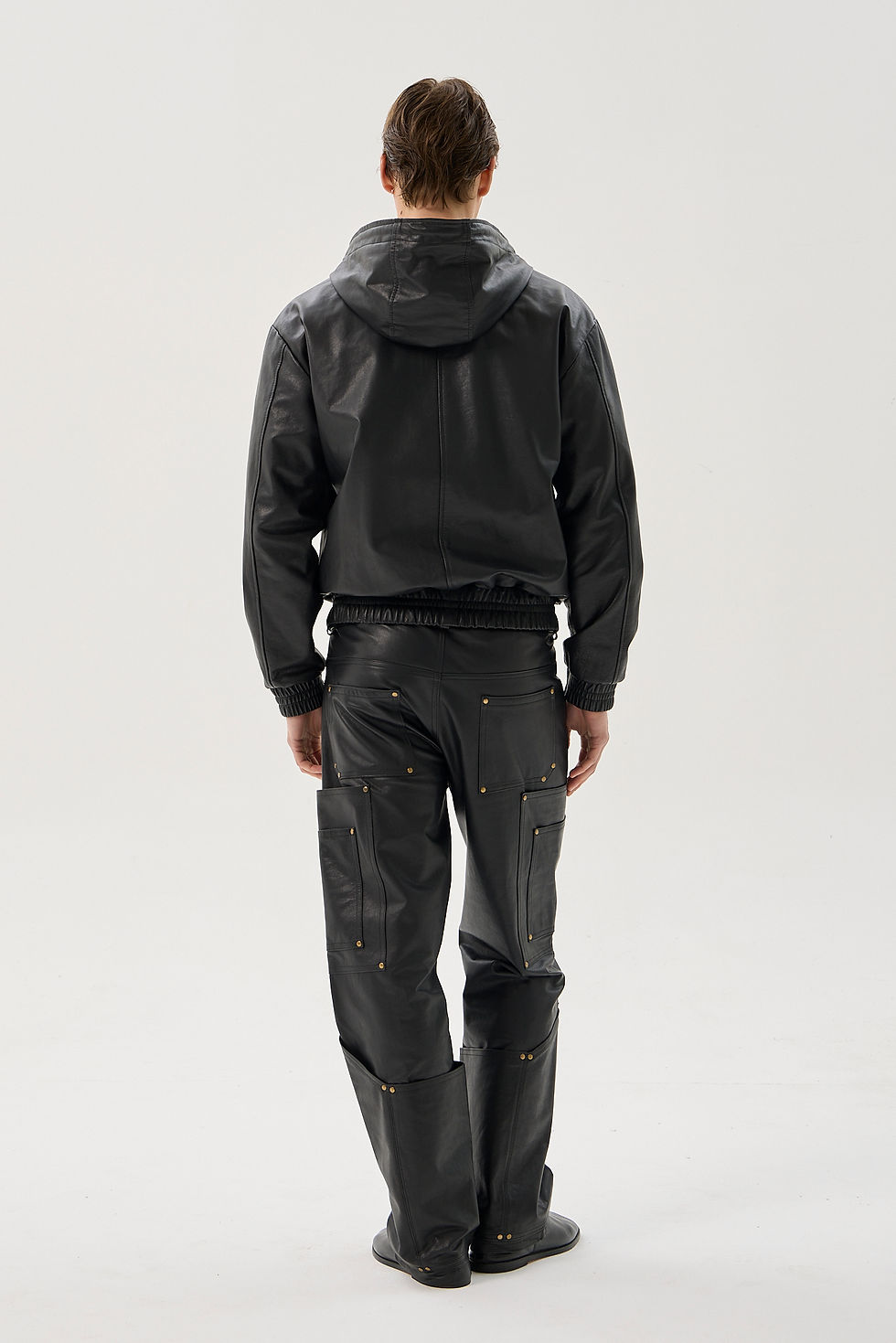 Black calfskin straight leg cargo trousers with reinforced utility pockets and brass rivets