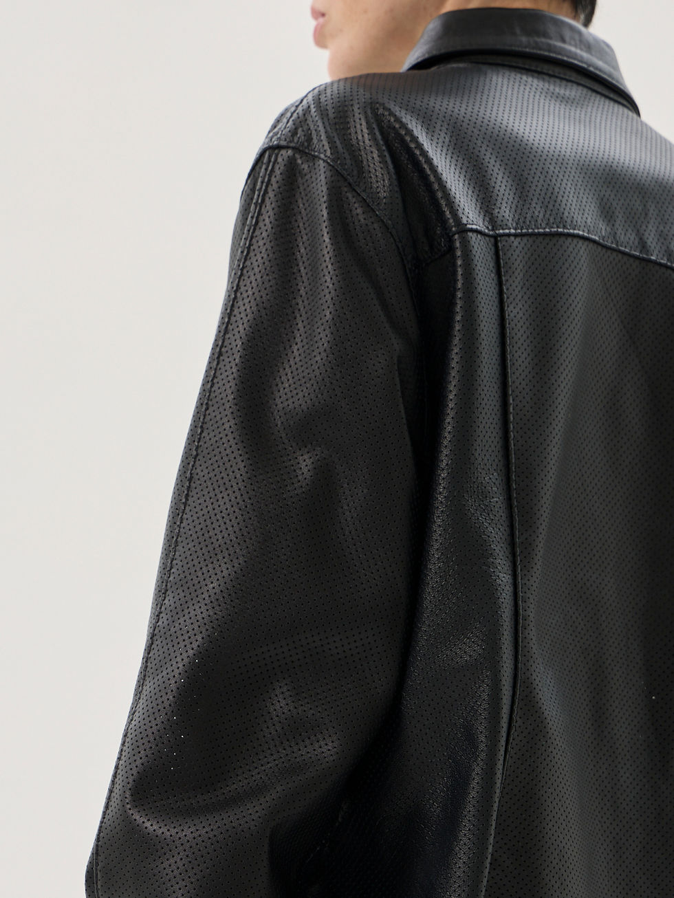 Black perforated sheepskin shirt with a classic collar, front snap closure, and curved hem