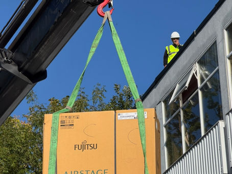 Crane lifting a condenser onto a roof.