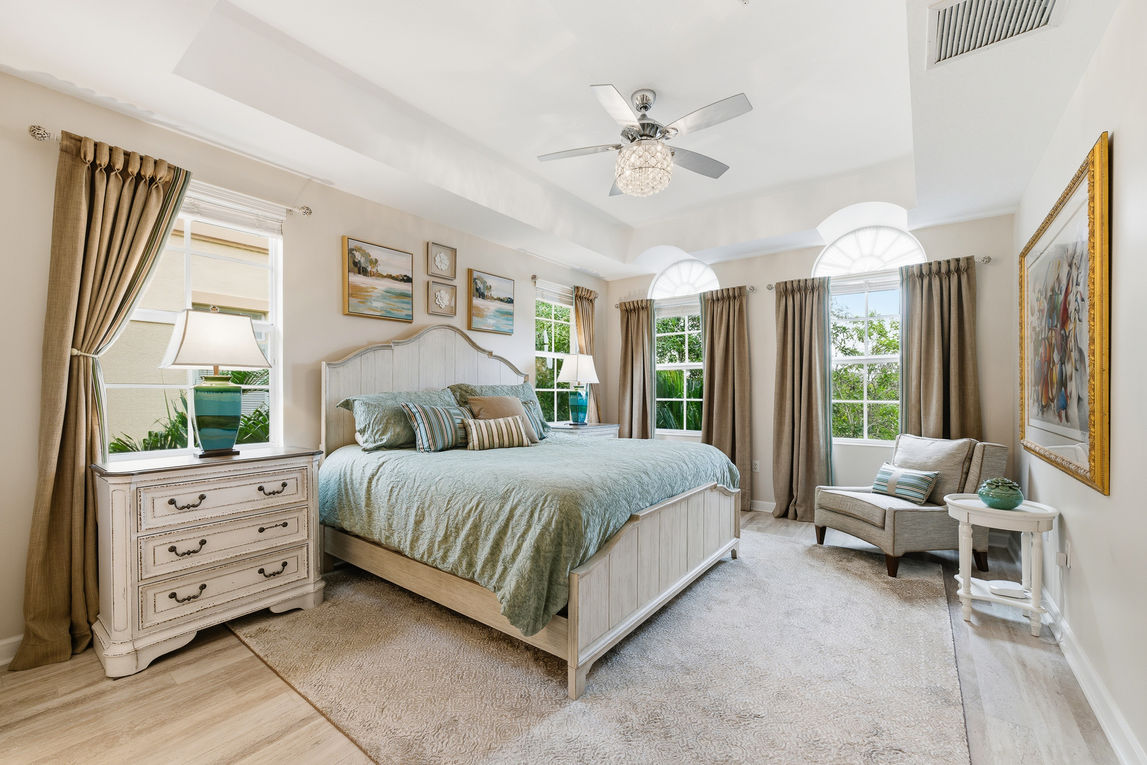 Primary bedroom in a Palm Beach condominium with large windows and natural light