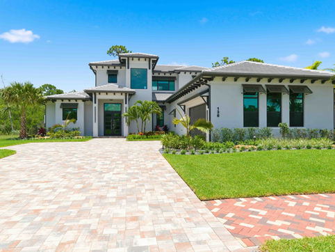 High-end real estate photography of a modern luxury home exterior in Port St. Lucie featuring contemporary architecture, manicured landscaping, and a paved driveway.