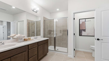 Builder model home primary bathroom in Port St. Lucie with double vanity and walk-in shower