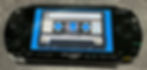 Black Sony PSP showing the TRAX cassette visualization, a tape with turning reels and an inlay card