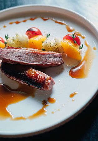 Close up of food styling of a white plate of smoked duck with orange sauce.jpg