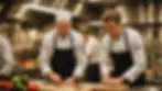An experienced chef guiding a young apprentice in a bustling kitchen