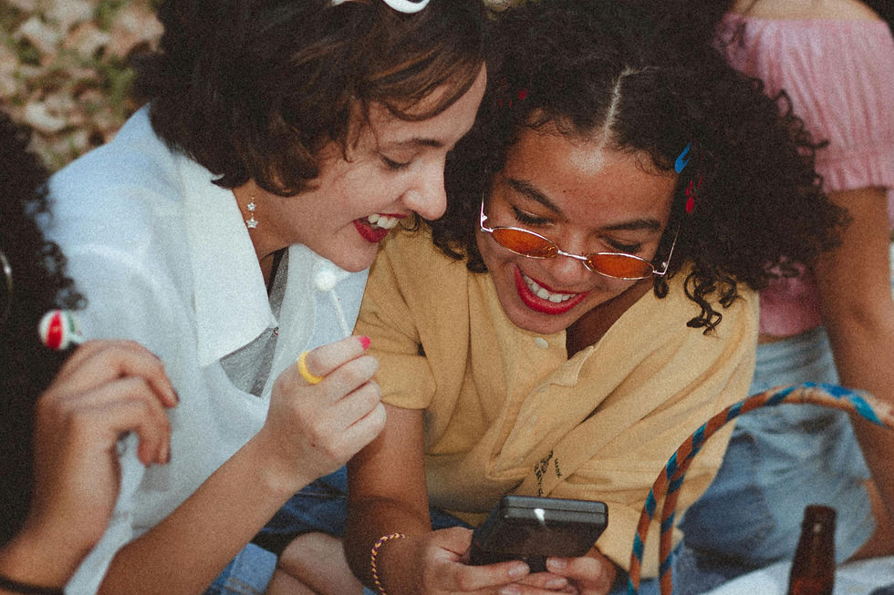 A couple girls at an outdoor friend gathering are laughing and exchanging contact details