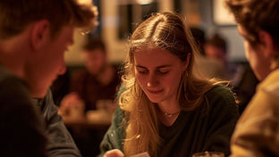 a group of young adults playing a card game in a pub