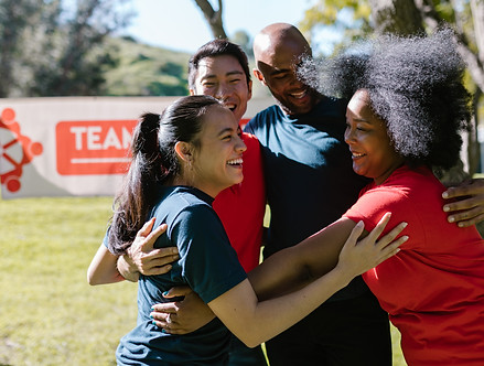 a group of 4 people are having a group hug after a team game