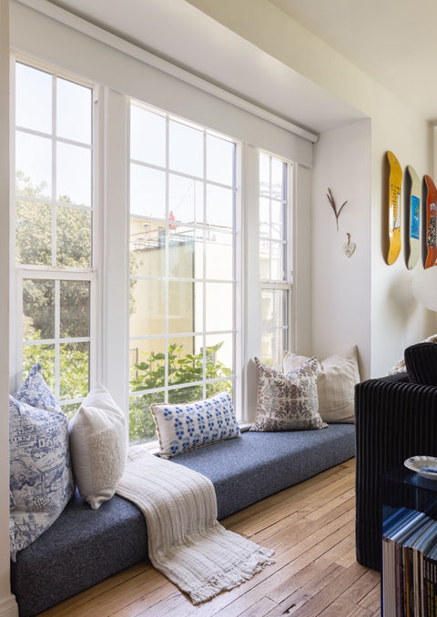 Modern living room with built-in window seat, neutral cushions, and large windows bringing in natural light. Bright and minimal home interior.