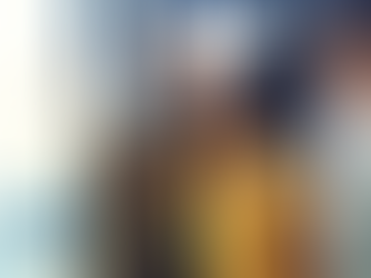 Three professionals smiling while a black female writes on a whiteboard.