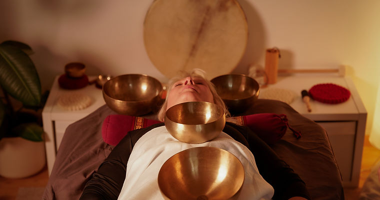 Frau mit Klangschalen auf dem Oberkörper