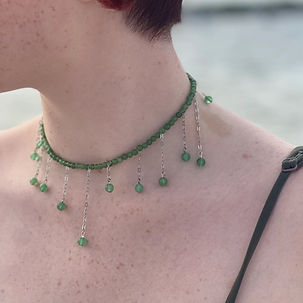 Closeup of an individual wearing a green beaded choker with dripping beads