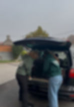 Zwei Personen beladen einen Kofferraum vor Ort in Bosnien.
