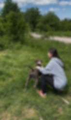 Frau hockt mit Hund auf einer Wiese vor Ort in Bosnien
