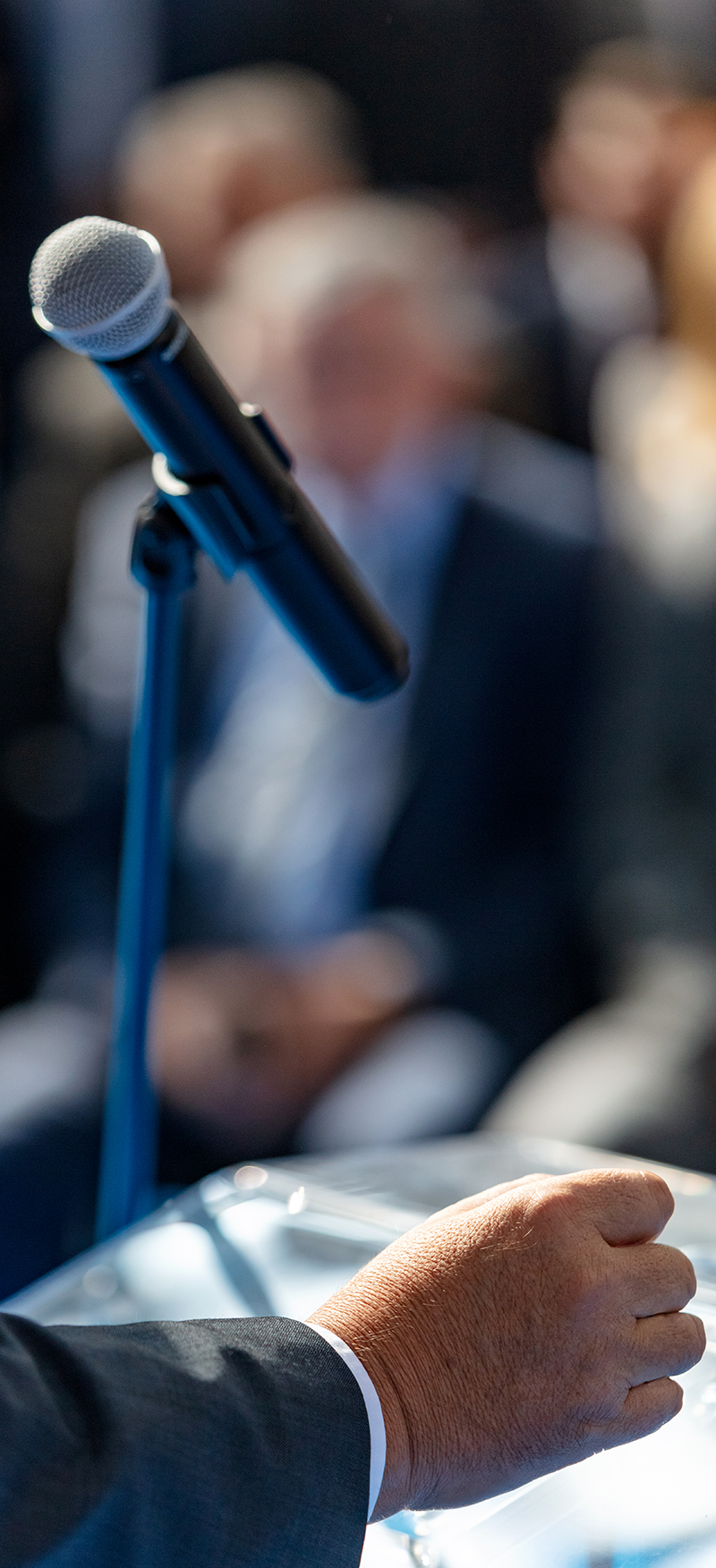 Close-up of a microphone, hand at podium, conference