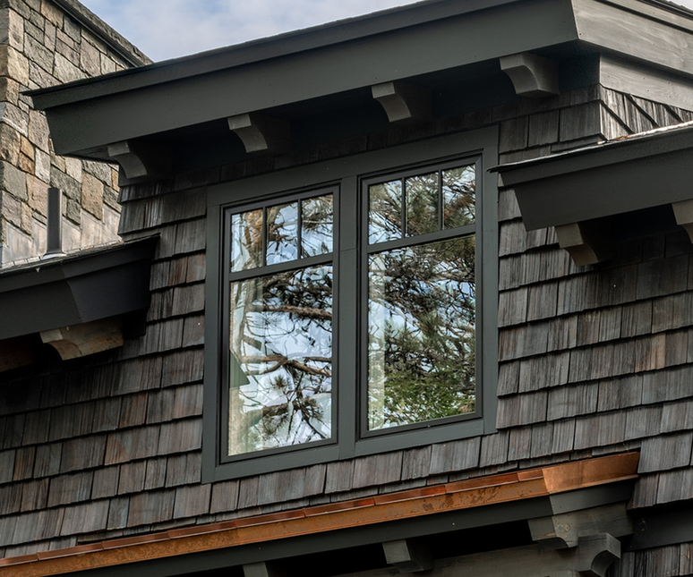 Dark gray dormers with black-framed windows reflecting trees