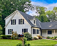 Two-story white house with black shutters and a mailbox.