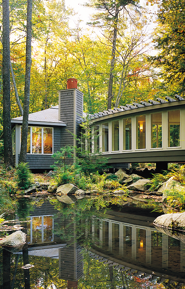 Modern house reflected in pond, autumn woods