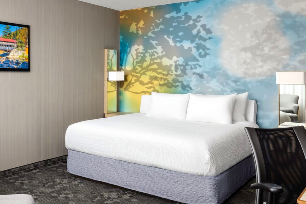 King-size bed in hotel room with tree mural