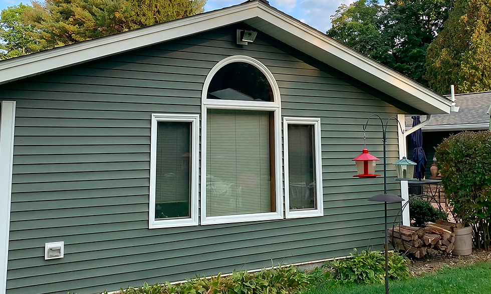 Green horizontal siding on a home with arched window.