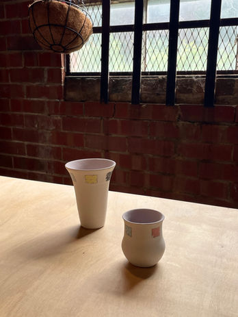 Two bisqued pots on a table in front of the studio window
