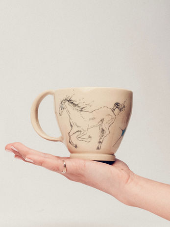 Mug with running horse design displayed on outstretched hand