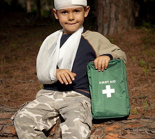 First Aid treatment given to a young boy in the forest, showing an arm sling and a head in