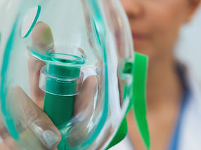 Female doctor holding up oxygen mask as if to put on patient in hospital