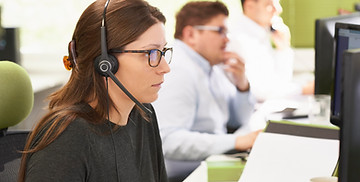 Une femme travaillant dans un call center assise à un bureau avec un micro