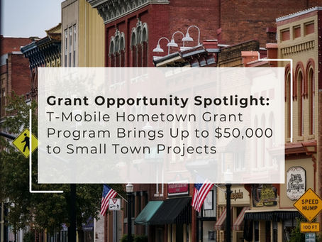 A street scene in a small town with historic brick buildings, storefronts, American flags, and street signs. Overlaid text reads: "Grant Opportunity Spotlight: T-Mobile Hometown Grant Program Brings Up to $50,000 to Small Town Projects."
