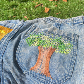 an embroidered image of a tree on a jean pocket