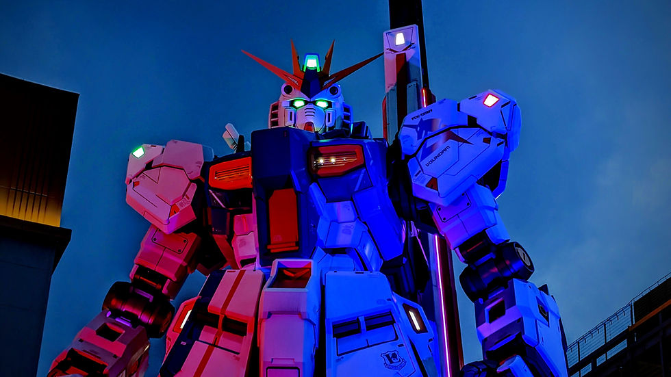 Giant robot statue lit in red and blue stands against a dusky sky. Its eyes glow brightly, evoking a futuristic and powerful presence.