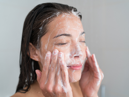 Woman rinsing her face with water at sink as part of daily skincare cleansing routine for healthy skin