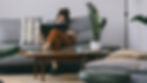 Lady sitting on a grey sofa, reading a book.
