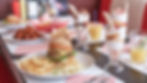 Milkshakes, burgers and chicken wings on a table.