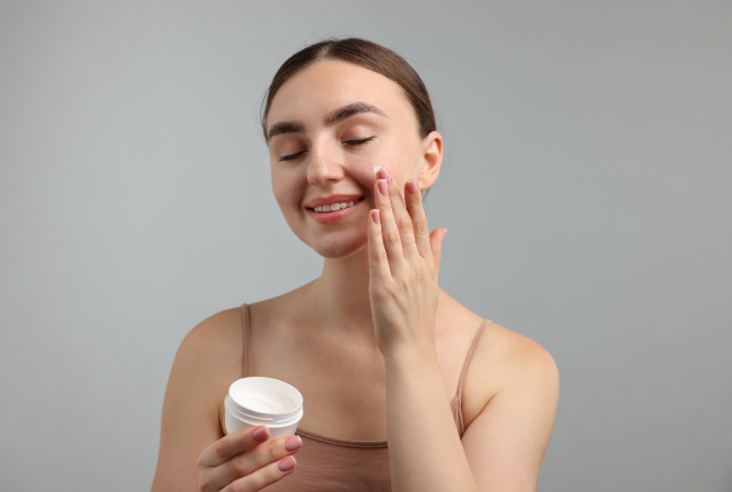 Woman applying facial moisturiser to hydrate and protect skin barrier