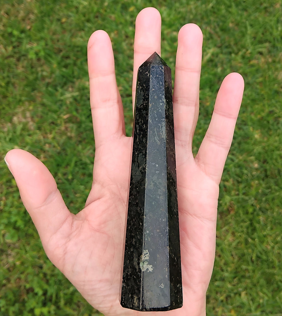 Specular Black Hematite Crystal Tower held in hand over grass