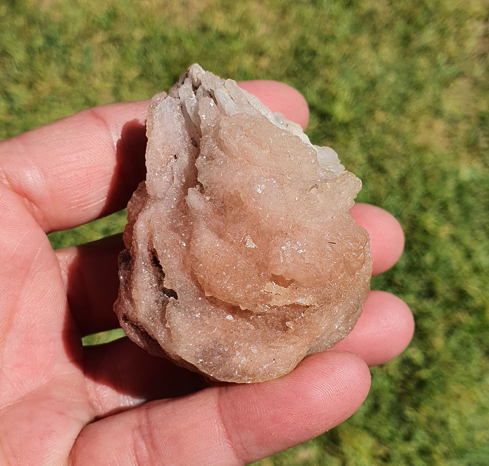 Hand holding raw pink stilbite drusy crystal cluster