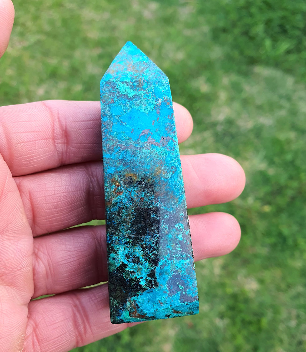Shattuckite and Chrysocolla crystal tower held against grass
