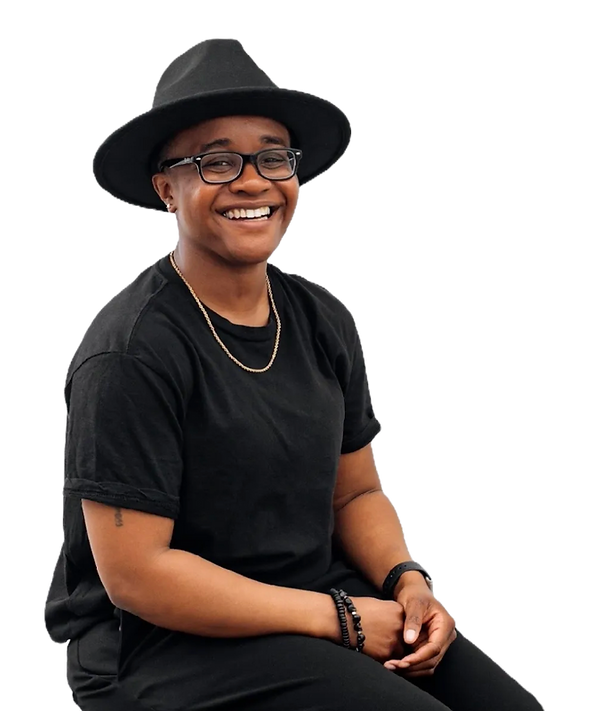 Coach AJ smiling in a black hat and glasses, professional coach and keynote speaker.