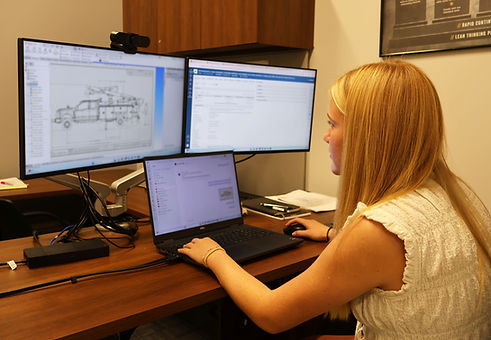 Young female intern working at Altec in advanced manufacturing, checking over truck blueprints