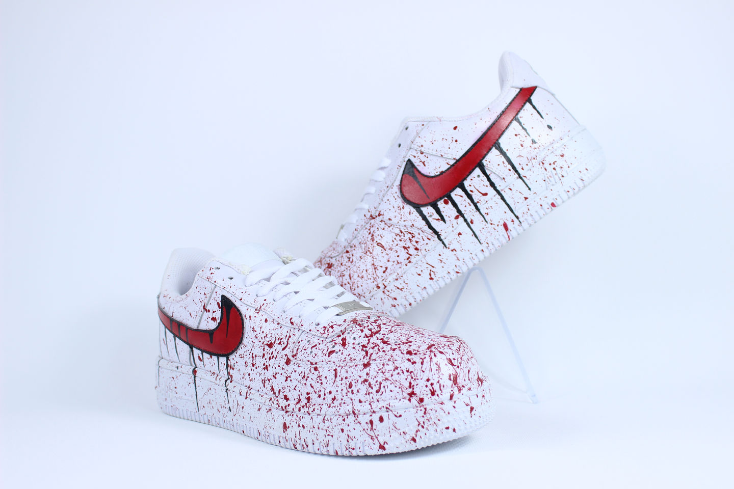 Side view of Bloody custom Nike Air Force 1 sneakers with red splatter paint resembling blood on white leather base