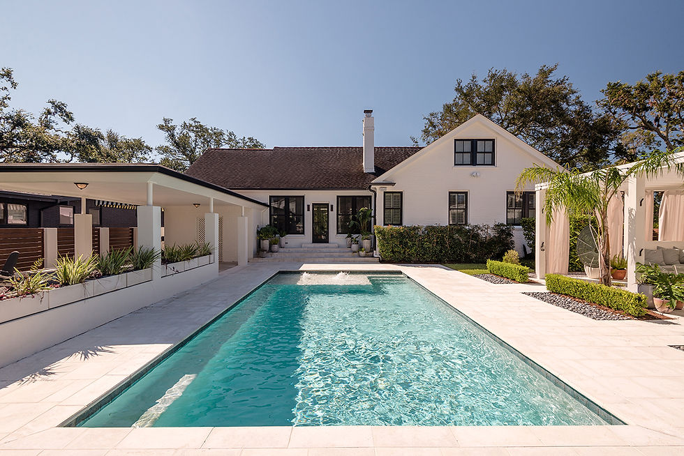 Swimming pool in foreground looking toward a white house with black trim