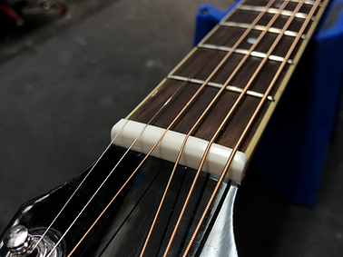 new polished and fitted bone nut for an acoustic guitar