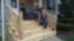 Worker on unfinished deck stairs outside a house