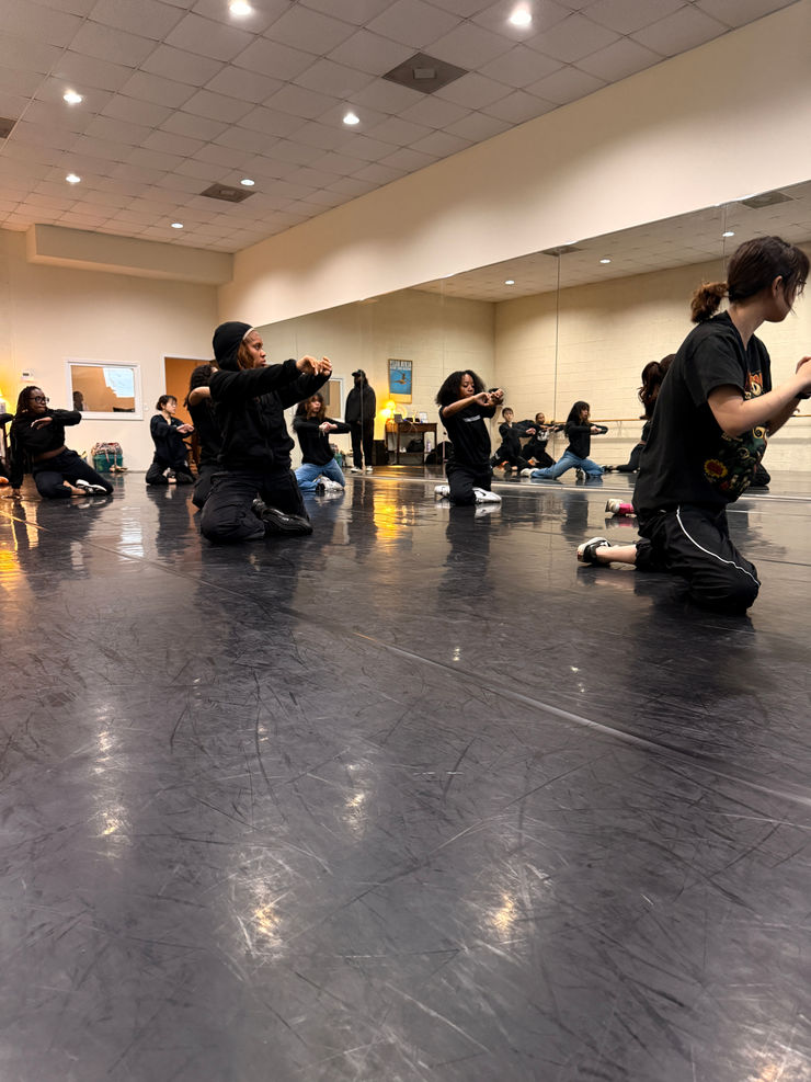 A dynamic group of dancers performing in a contemporary studio setting