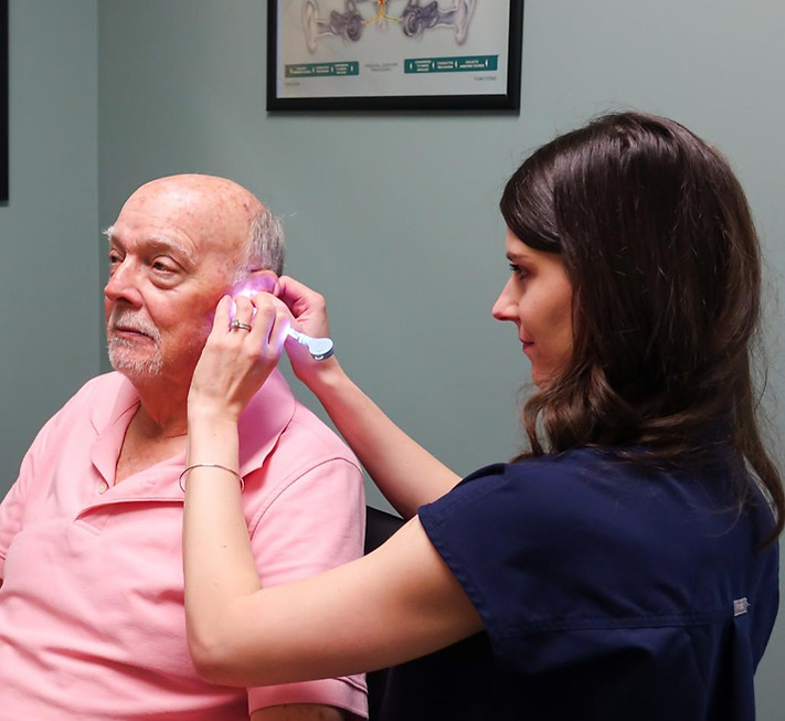 Specialist examining a senior man's ear with an otoscope