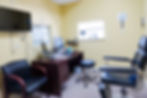 Medical exam room with desk, computer, and patient chair.