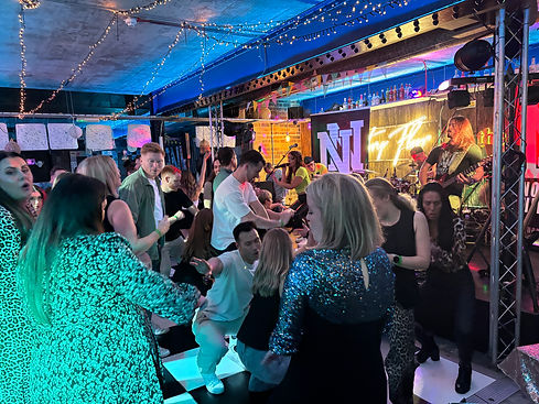 Noughty Nineties performing their high energy party set of 90s and 00s songs at a club. The dancefloor is full.