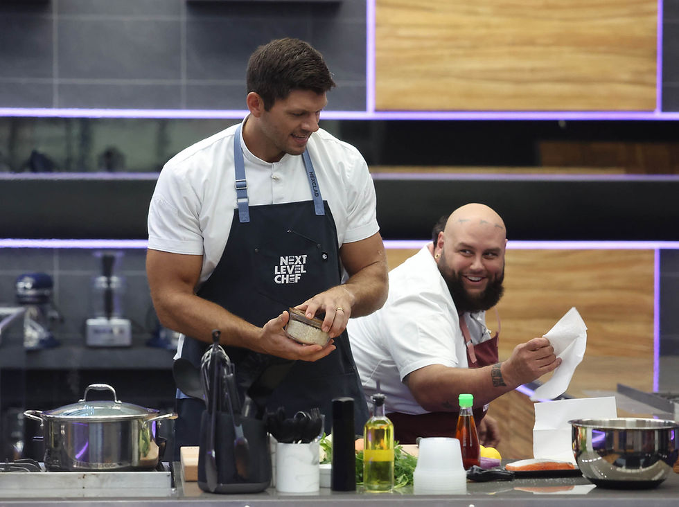 Two chefs in a modern kitchen, one holding a container, the other smiling with a paper towel. "Next Level Chef" on apron. Mood is lively.